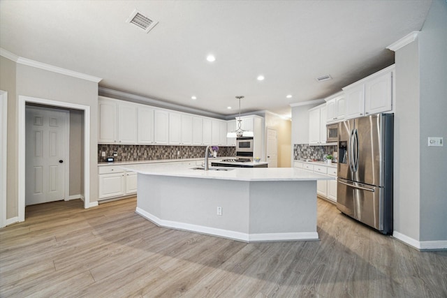 kitchen with white cabinetry, decorative light fixtures, an island with sink, and appliances with stainless steel finishes