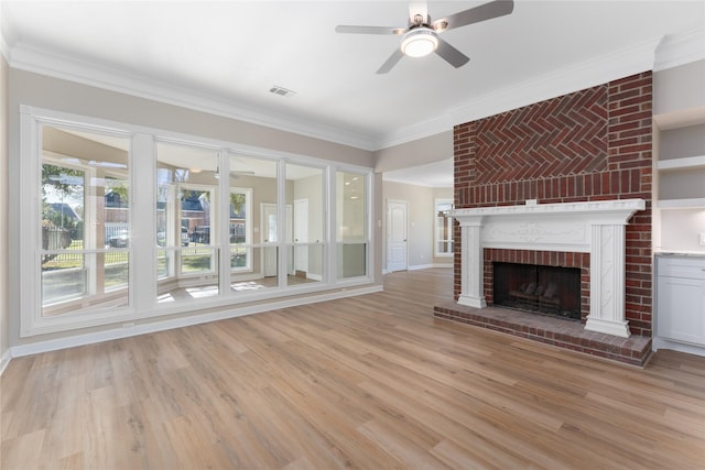 unfurnished living room with ceiling fan, crown molding, a fireplace, and light hardwood / wood-style flooring