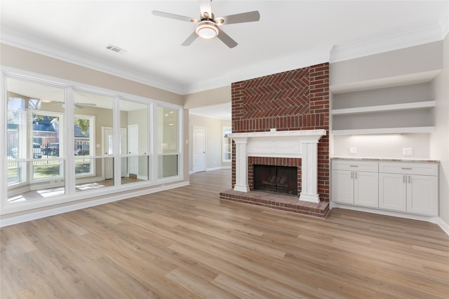 unfurnished living room with ceiling fan, ornamental molding, light hardwood / wood-style flooring, and a brick fireplace