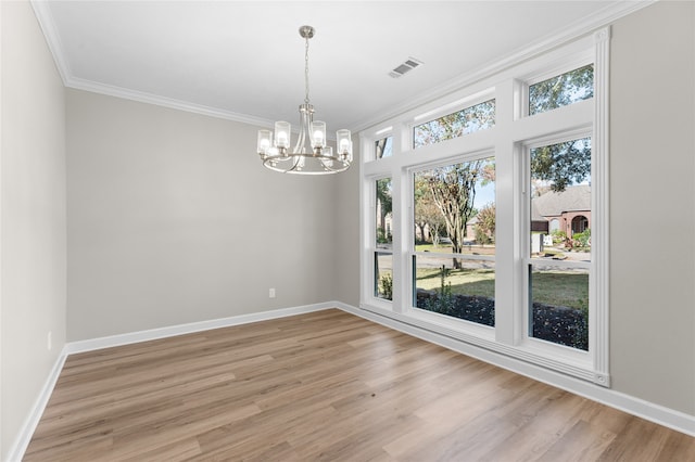 spare room featuring light hardwood / wood-style flooring, an inviting chandelier, and crown molding