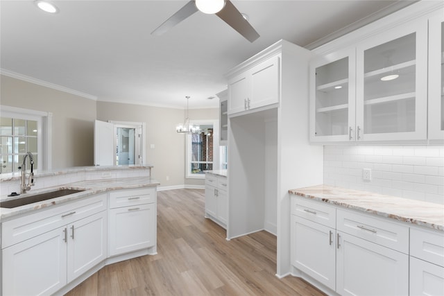 kitchen with sink, tasteful backsplash, decorative light fixtures, white cabinets, and light wood-type flooring