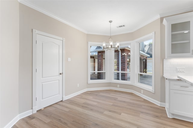 unfurnished dining area featuring light hardwood / wood-style flooring, ornamental molding, and an inviting chandelier