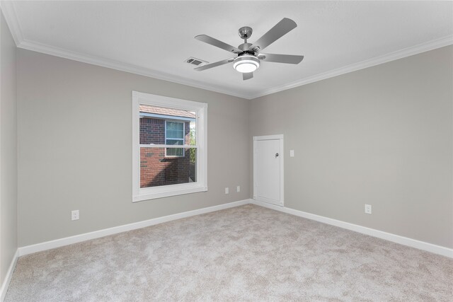 empty room with ceiling fan, crown molding, and light carpet