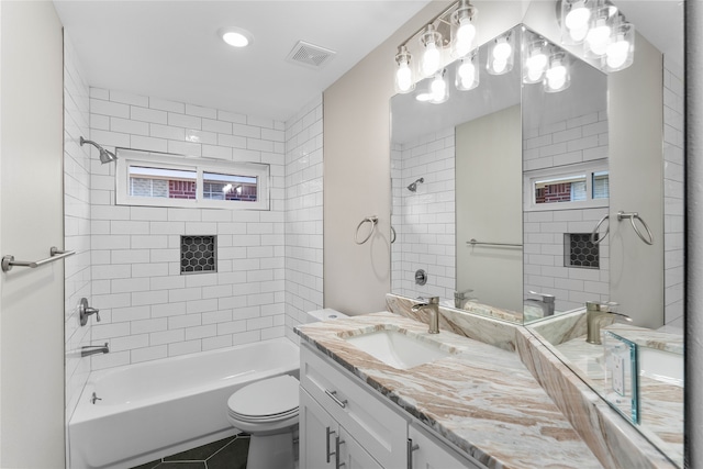 full bathroom with tile patterned floors, vanity, tiled shower / bath, and toilet