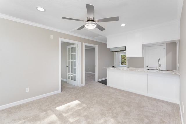 kitchen with crown molding, white cabinets, light carpet, and ceiling fan