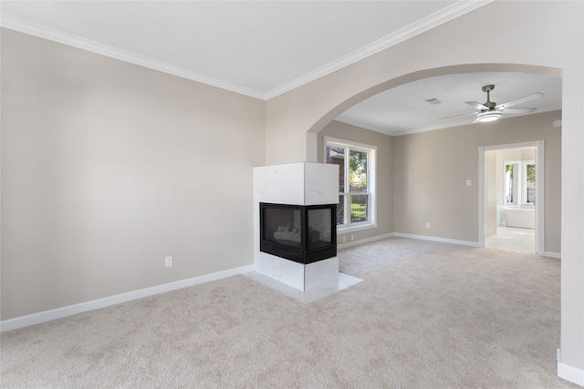 unfurnished living room with light carpet, ornamental molding, a healthy amount of sunlight, and a tiled fireplace