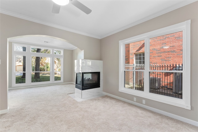 unfurnished living room with light carpet, crown molding, a fireplace, and a healthy amount of sunlight