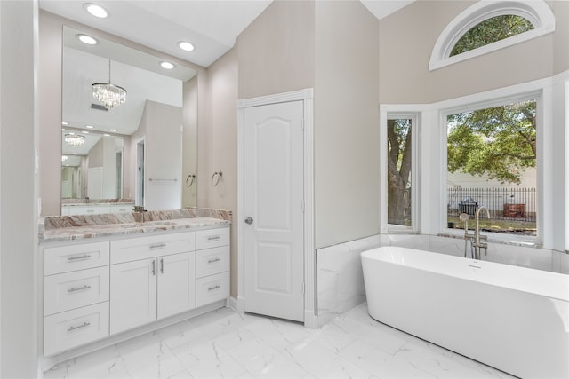 bathroom with a towering ceiling, a washtub, vanity, and an inviting chandelier