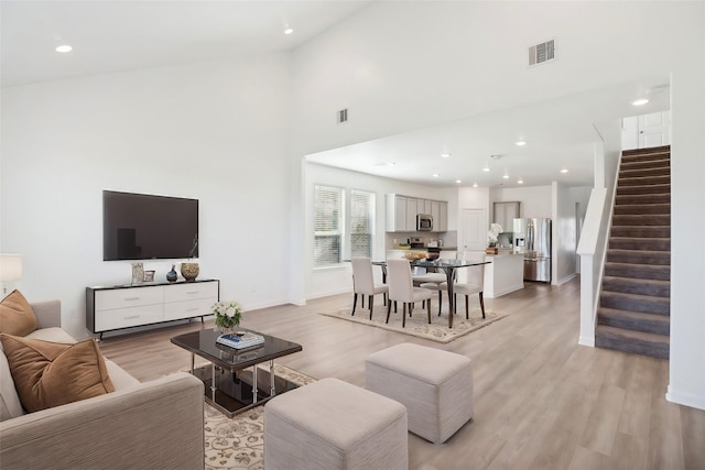 living room featuring a towering ceiling and light hardwood / wood-style floors