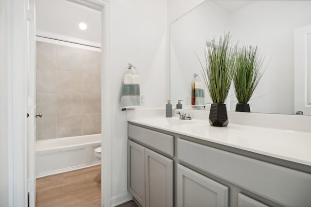 full bathroom with wood-type flooring, toilet, tiled shower / bath combo, and vanity