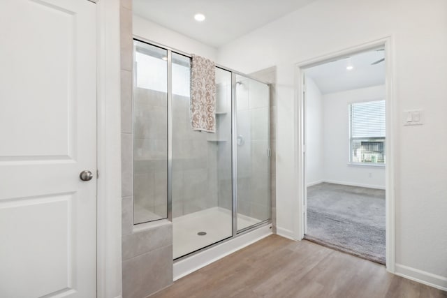 bathroom with a shower with shower door and hardwood / wood-style floors