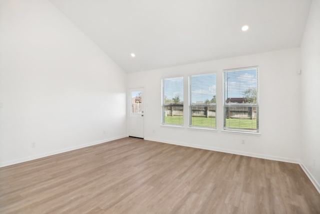 spare room with lofted ceiling and light wood-type flooring