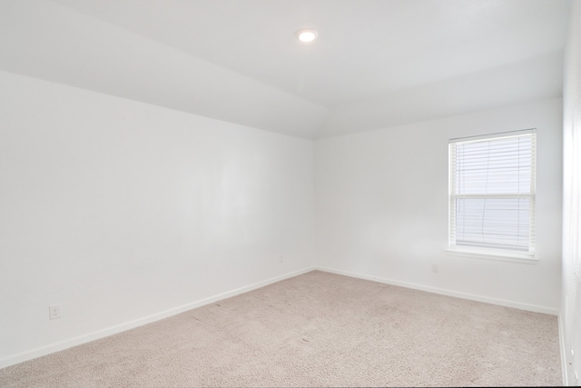 carpeted spare room featuring lofted ceiling