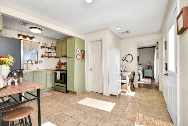 kitchen with ornamental molding, sink, light tile patterned floors, stainless steel electric range oven, and green cabinets