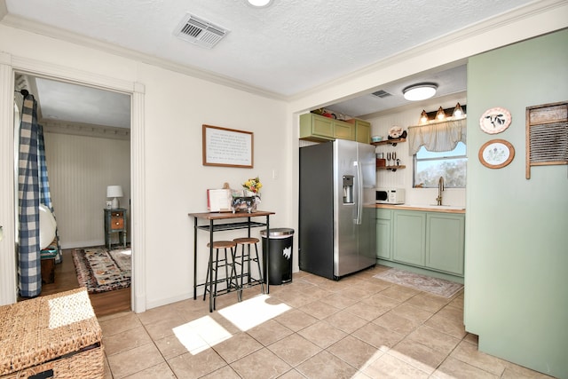 kitchen featuring green cabinets, sink, a textured ceiling, light tile patterned flooring, and stainless steel fridge with ice dispenser