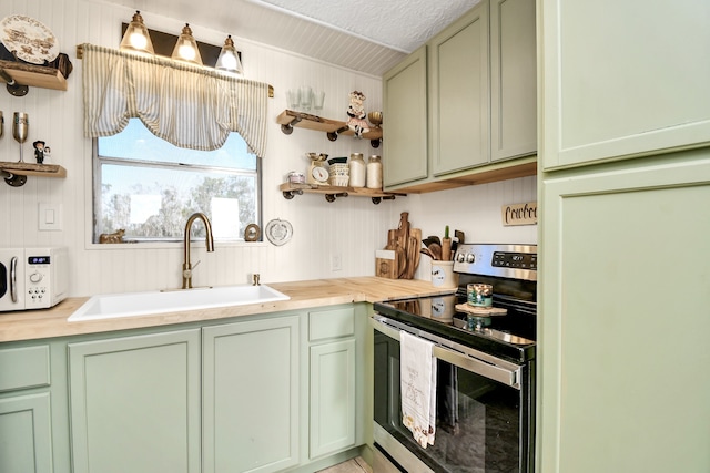 kitchen with green cabinets, butcher block counters, sink, and stainless steel range with electric stovetop