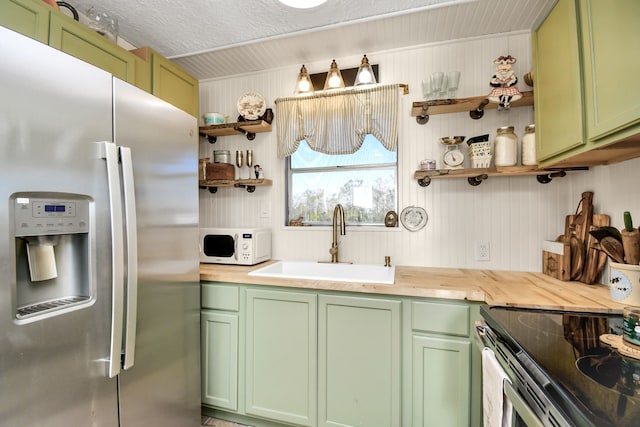 kitchen with sink, wood counters, stainless steel refrigerator with ice dispenser, a textured ceiling, and green cabinetry