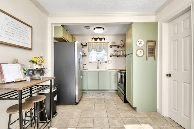 kitchen featuring a textured ceiling, stainless steel appliances, crown molding, green cabinetry, and light tile patterned flooring