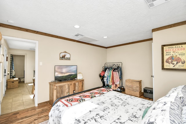 bedroom featuring hardwood / wood-style floors, crown molding, and a textured ceiling