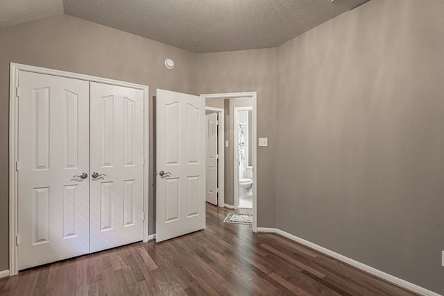 unfurnished bedroom with a textured ceiling, dark hardwood / wood-style floors, vaulted ceiling, and a closet