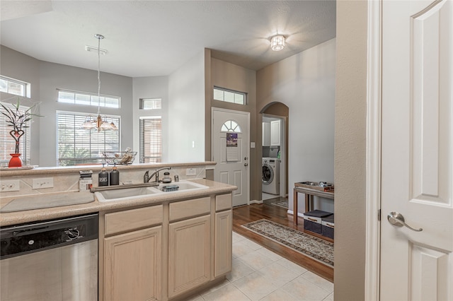 kitchen featuring sink, an inviting chandelier, dishwasher, washer / dryer, and light hardwood / wood-style floors