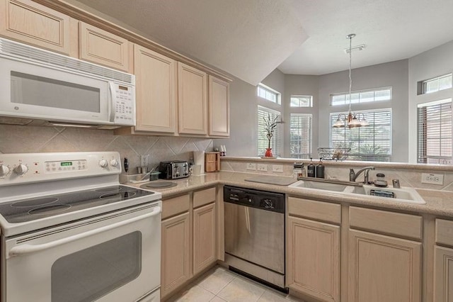 kitchen featuring a healthy amount of sunlight, white appliances, sink, and light tile patterned floors