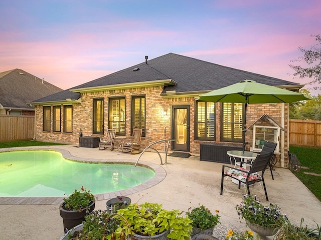 pool at dusk featuring a patio