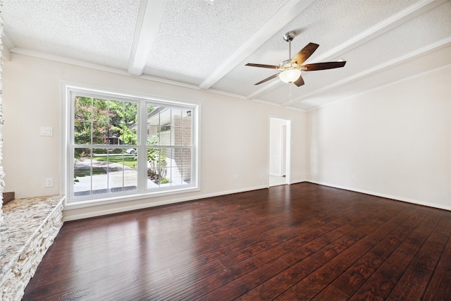 spare room featuring ceiling fan, dark wood-type flooring, beamed ceiling, a textured ceiling, and a fireplace