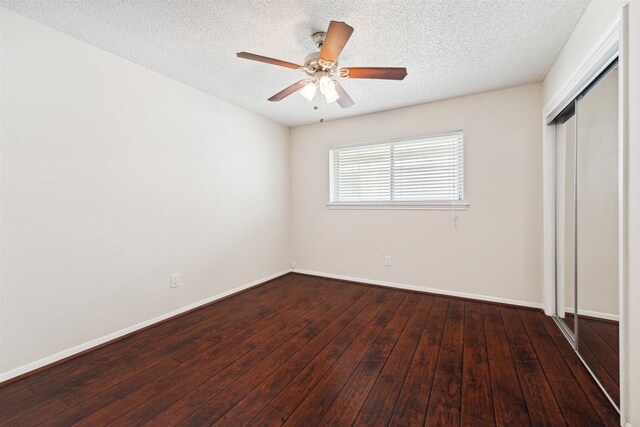 unfurnished bedroom featuring ceiling fan, dark hardwood / wood-style flooring, a textured ceiling, and a closet