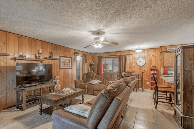 tiled living room with ceiling fan, a textured ceiling, and wooden walls