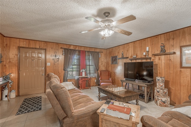 living room featuring light tile patterned flooring, a textured ceiling, ceiling fan, and wooden walls