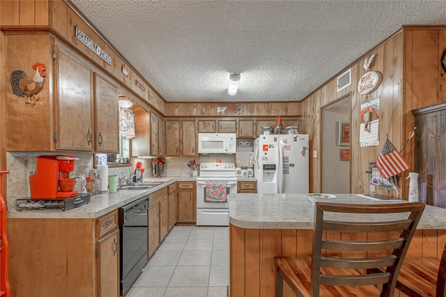 kitchen featuring light tile patterned flooring, sink, a breakfast bar area, a textured ceiling, and white appliances