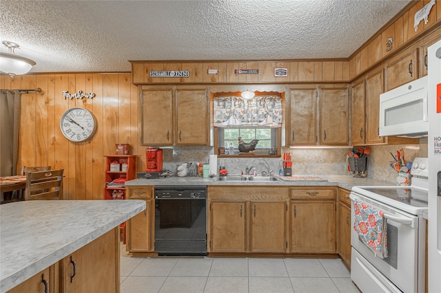 kitchen with wooden walls, sink, light tile patterned floors, white appliances, and a textured ceiling