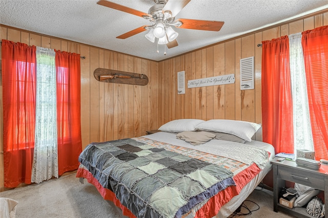 bedroom with light carpet, a textured ceiling, ceiling fan, and wood walls