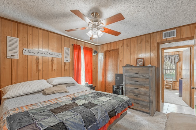 carpeted bedroom featuring ceiling fan, a textured ceiling, and wood walls