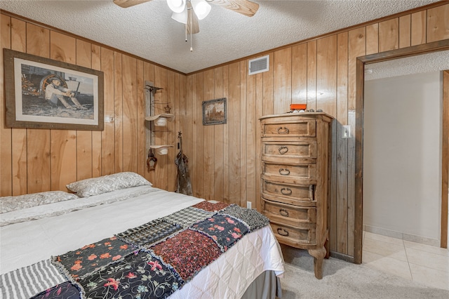 carpeted bedroom with a textured ceiling, ceiling fan, and wood walls