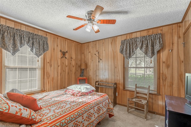 bedroom featuring light colored carpet, a textured ceiling, ceiling fan, and wood walls