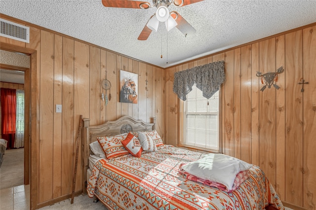 bedroom featuring wooden walls, light colored carpet, and ceiling fan