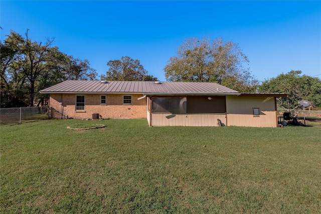 rear view of property featuring a sunroom, central AC unit, and a lawn