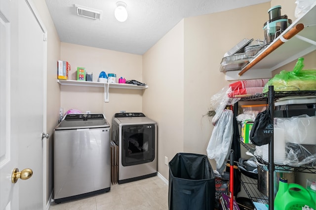 laundry room with a textured ceiling and washing machine and clothes dryer