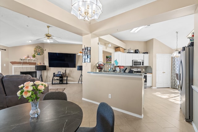 dining room featuring a fireplace, ceiling fan with notable chandelier, vaulted ceiling, and light tile patterned floors