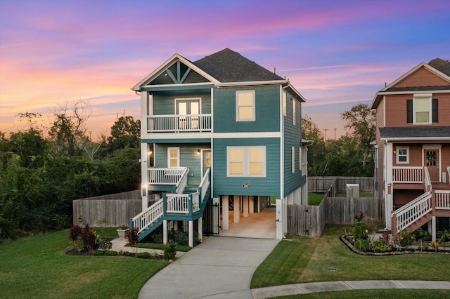 coastal inspired home featuring a yard, a balcony, and a carport