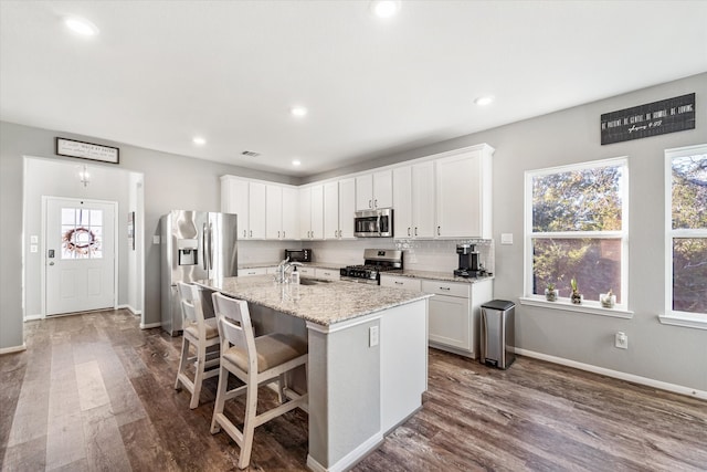 kitchen featuring white cabinetry, a center island with sink, stainless steel appliances, and hardwood / wood-style flooring