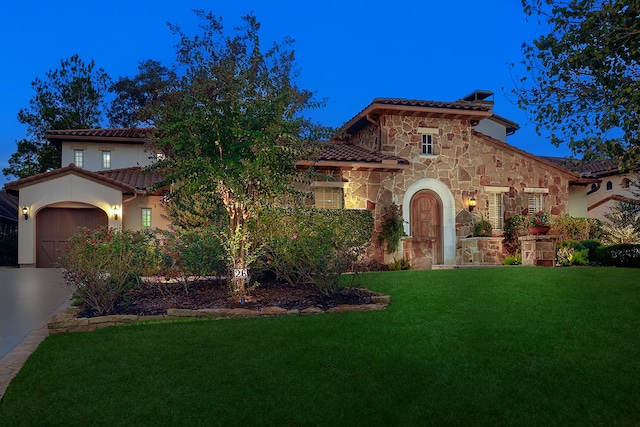 mediterranean / spanish home featuring a front yard and a garage