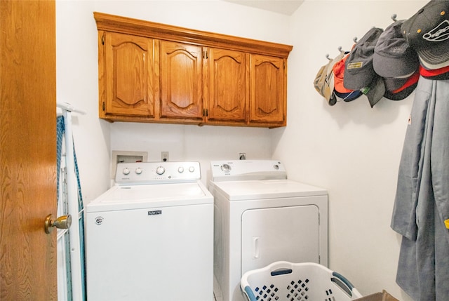 clothes washing area with cabinets and washing machine and clothes dryer