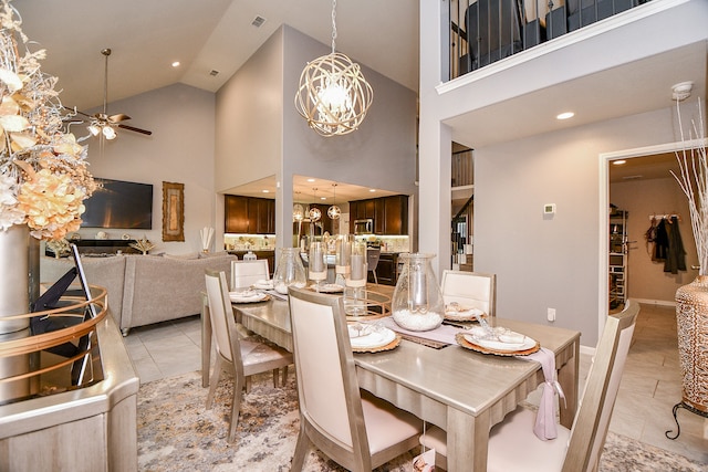 tiled dining space with ceiling fan with notable chandelier and high vaulted ceiling