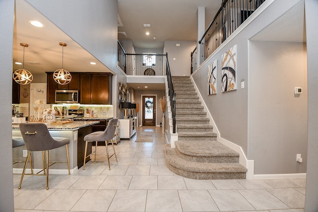 kitchen with pendant lighting, light tile patterned floors, tasteful backsplash, light stone counters, and a breakfast bar area