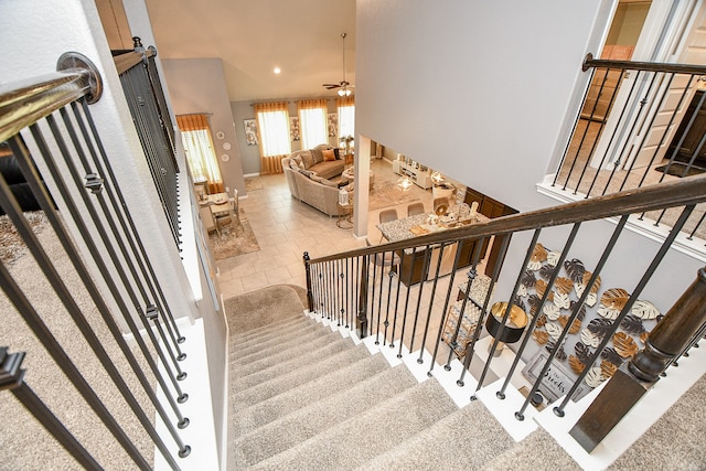 staircase featuring tile patterned floors and ceiling fan