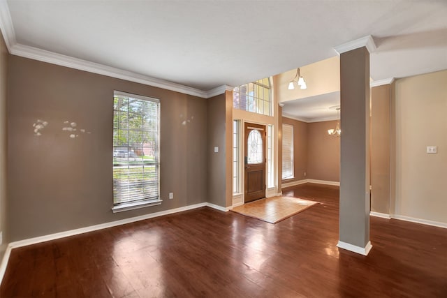 entryway with dark hardwood / wood-style floors, ornamental molding, and an inviting chandelier