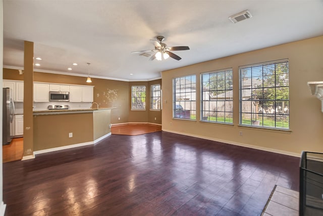 unfurnished living room featuring a wealth of natural light, crown molding, ceiling fan, and dark hardwood / wood-style floors